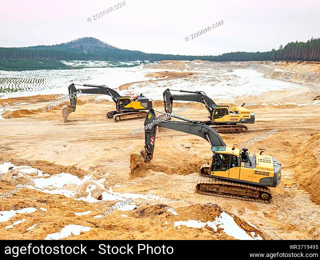 Loading excavators rest during the weekend. A large mine on white glass sand with several floors