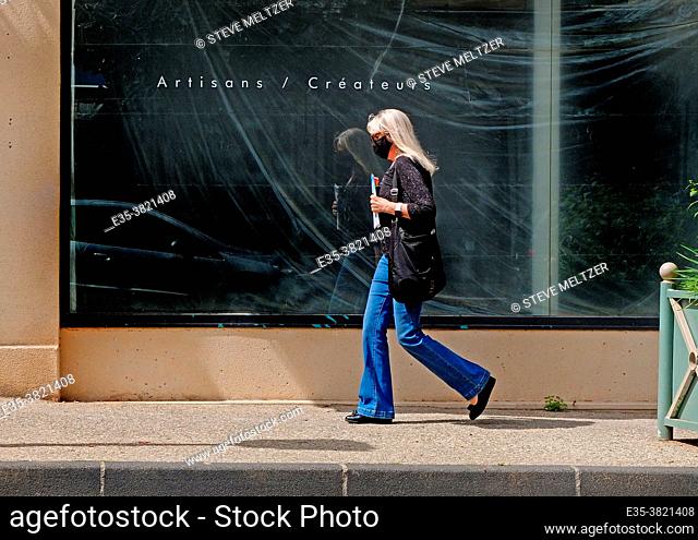 During the 2021 confinement a woman strides past an empty shop