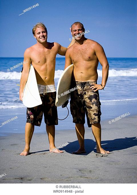 Two males on beach with their surf boards