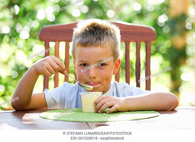 Cute little boy eating oudding outside