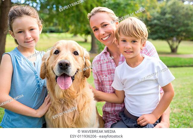 Happy family looking at camera and playing with their dog