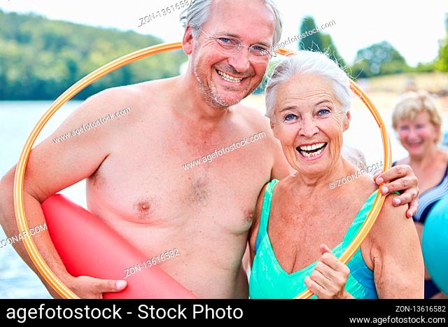 Lachendes vitales Senioren Paar im Sommerurlaub mit einem Reifen und Yogamatte