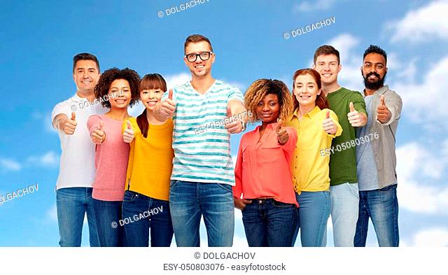 diversity, race, ethnicity and people concept - international group of happy smiling men and women showing thumbs up over blue sky and clouds background