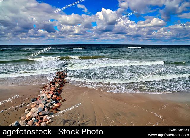 Old breakwater on the sandy beach of the Baltic sea in Sunny summer day