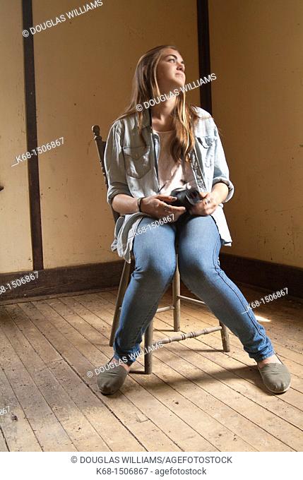 15 year old girl sits in an old abandoned house with her camera