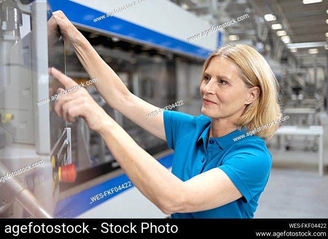 Blond woman operating machinery in factory