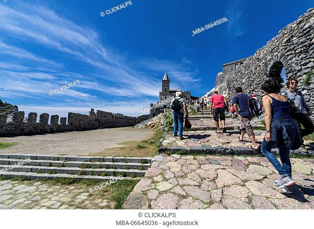 Tourists beside the medieval wall that leads to old castle and church Portovenere province of La Spezia Liguria Italy Europe