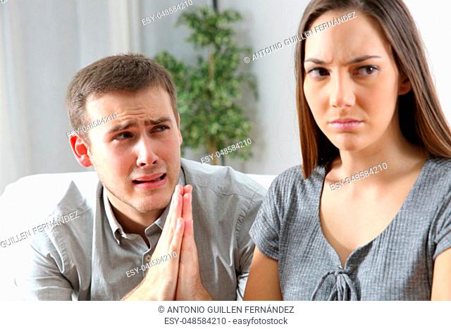 Husband asking for forgiveness to his ex wife after conflict sitting in a couch in a house