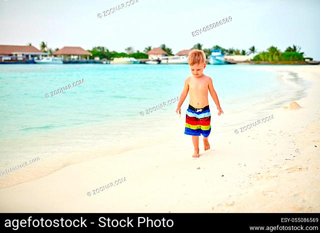 Three year old toddler boy on beach at sunset. Summer family vacation at Maldives