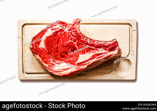 Raw beef prime rib on a cutting board isolated on white background. Top view