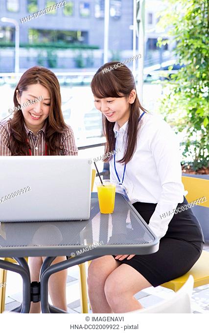 Business women using a computer at an outdoor cafe