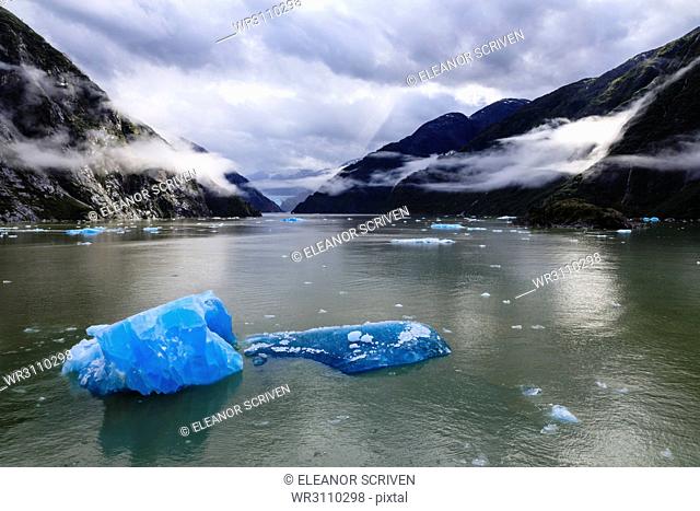 Spectacular Tracy Arm Fjord, brilliant blue icebergs and backlit clearing mist, mountains and South Sawyer Glacier, Alaska, United States of America