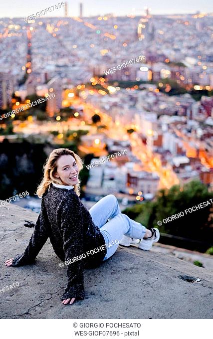 Portrait of happy young woman at dawn above the city, Barcelona, Spain