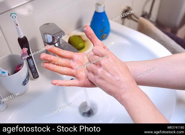 Woman washing her hands thoroughly in bathroom
