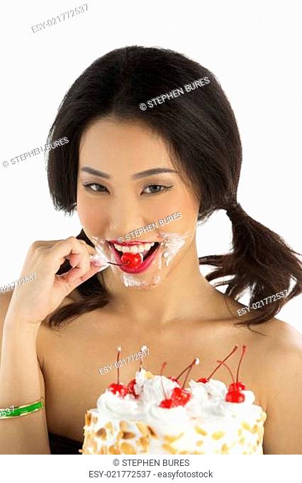 Asian girl eating cherry from birthday cake