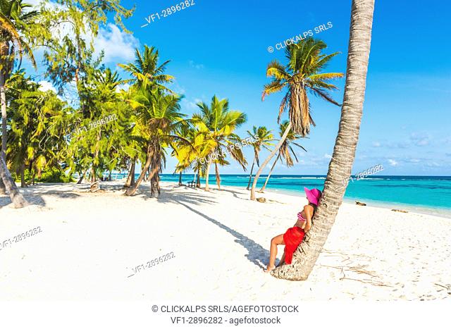 Canto de la Playa, Saona Island, East National Park (Parque Nacional del Este), Dominican Republic, Caribbean Sea. Beautiful woman with red sarong relaxing on...