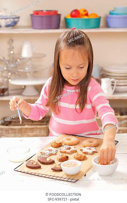 A girl decorating biscuits with sugar pearls