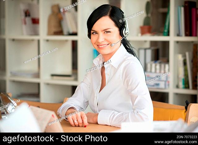 She like to speak with clients on phone. Portrait of white collar worker with headphones in office