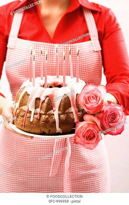 Woman holding ring cake and roses for a birthday
