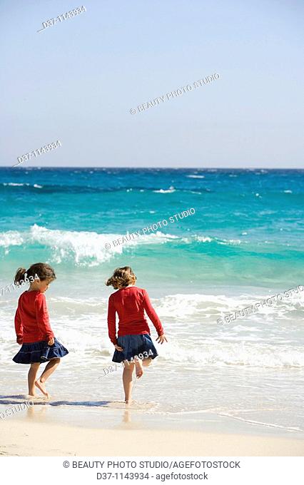 Two caucasian girls by the sea playing