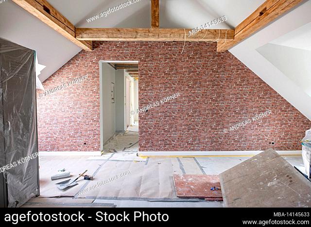 construction site, refurbishment and renovation of an apartment, empty room in the attic with brick motif wallpaper