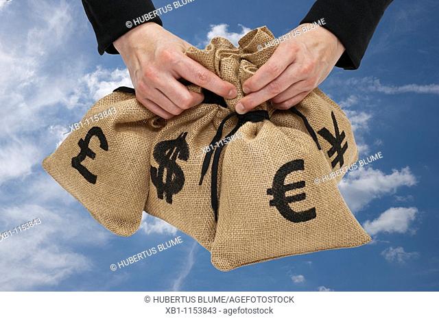 four money bags with €, euro, yen, pound and dollar signs are hand-held
