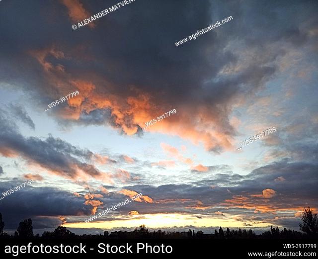Evening landscape with beautiful pale picturesque clouds. Evening landscape with clouds. Dark clouds during sunset. Beautiful sunset with bright clouds