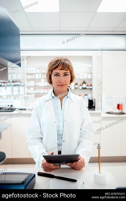Female professional with digital tablet standing at pharmacy