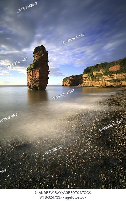 A sandstone sea stack towering above the beach at Ladram Bay in South East Devon. A long shutter speed was utilized to blur the movement in the clouds on an...