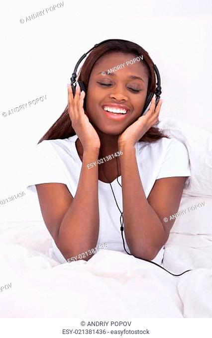 Happy African American woman enjoying music through headphones