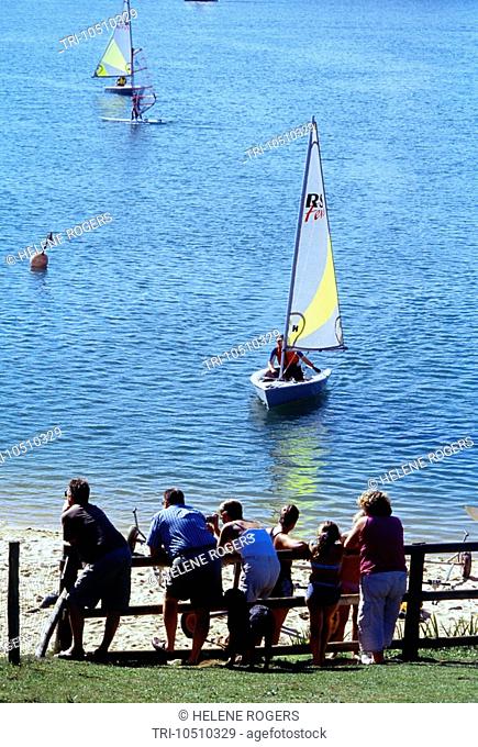 Sailing Dingys on Lake with People Watching in Mercers Park Mersham Surrey England
