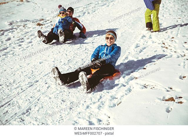 Italy, Val Venosta, Slingia, family sleighing down a snowy hill