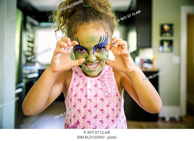 Mixed race girl growling with face paint