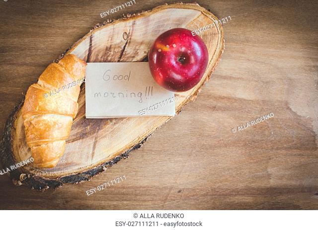 Apple, Croissant and Good Morning Note on Rustic Wooden Background. Selective Focus. Concept Breakfast. Toned image