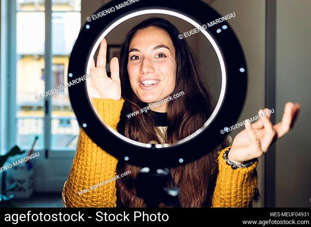 Vlogger gesturing in front of ring light at home