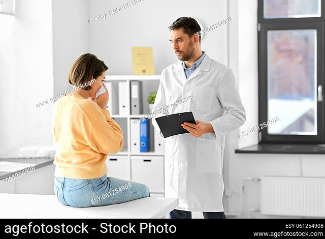 male doctor and woman blowing nose at hospital