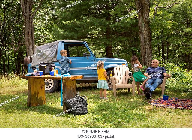 Father and children sitting in woods beside off road vehicle