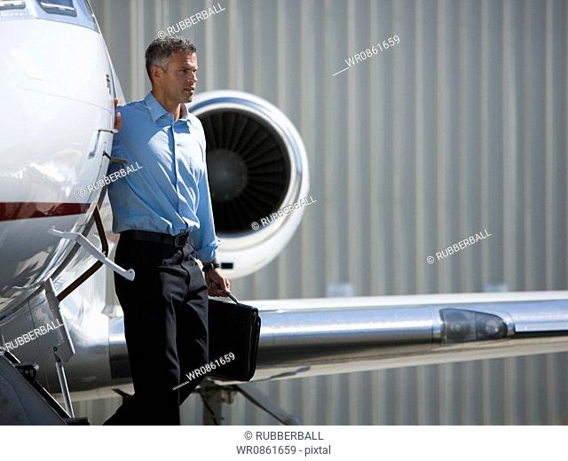 Profile of a businessman exiting an airplane