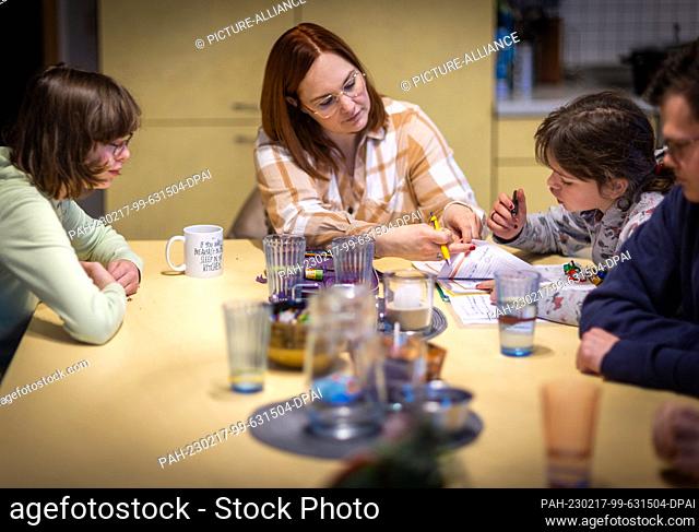 PRODUCTION - 12 January 2023, Mecklenburg-Western Pomerania, Wolgast: Nadine Deutschmann sits with some of the children at the large table in the kitchen and...