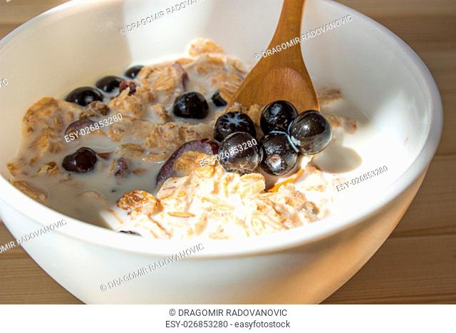 White bowl with healthy breakfast. Aronia and other berries with spelta in milk