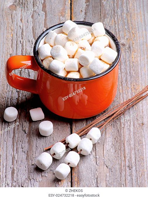 Orange Cup with Hot Chocolate and Marshmallows on Wooden Stems isolated on Rustic Wooden background