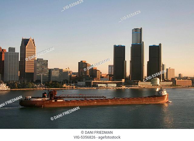 A large bulk carrier cargo ship travels along the Detroit River with the skyline of downtown Detroit, Michigan, USA in the background