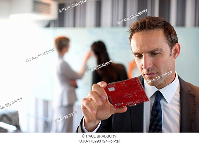 Businessman looking at circuit board in office