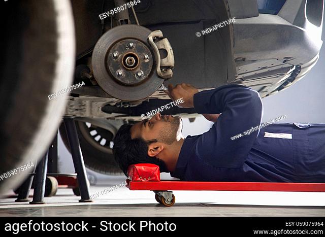 A car mechanic working on the underside of a car