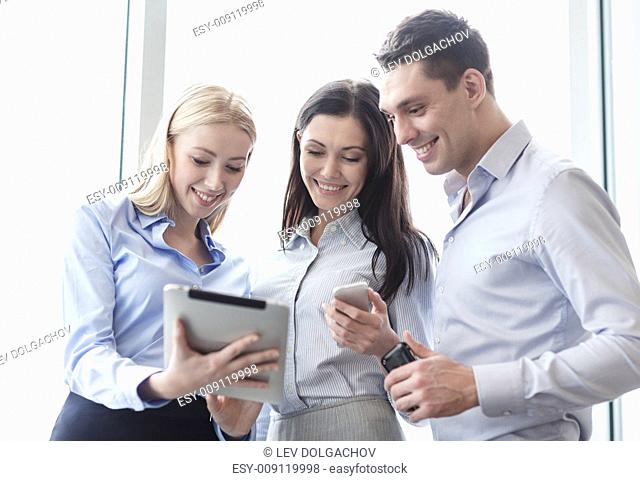 business and office concept - smiling business team working with tablet pcs and smartphones in office