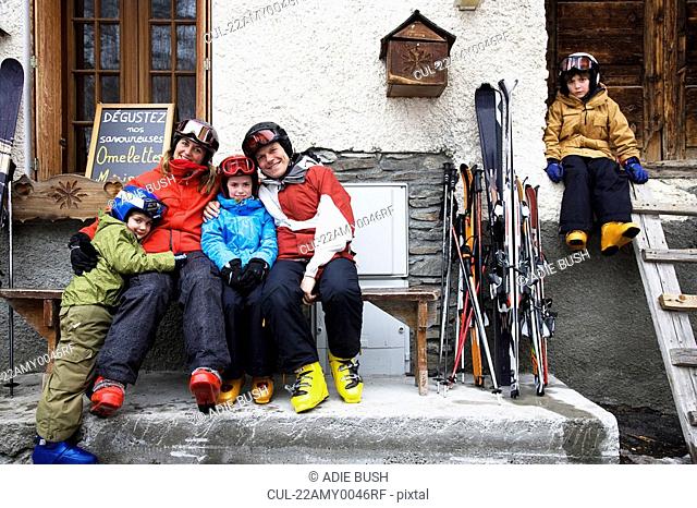 Family sitting outside barn with skis