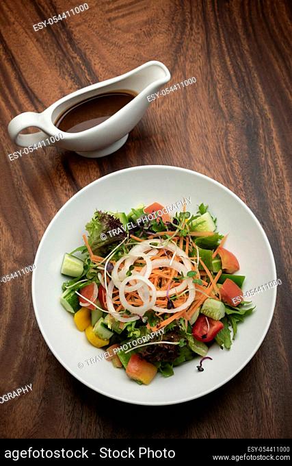 fresh organic mixed vegetable vegan Garden Salad with Vinaigrette sauce on wooden table