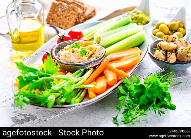 Platter of assorted fresh vegetables with avocado dip, hummus, marinated mushrooms and olives