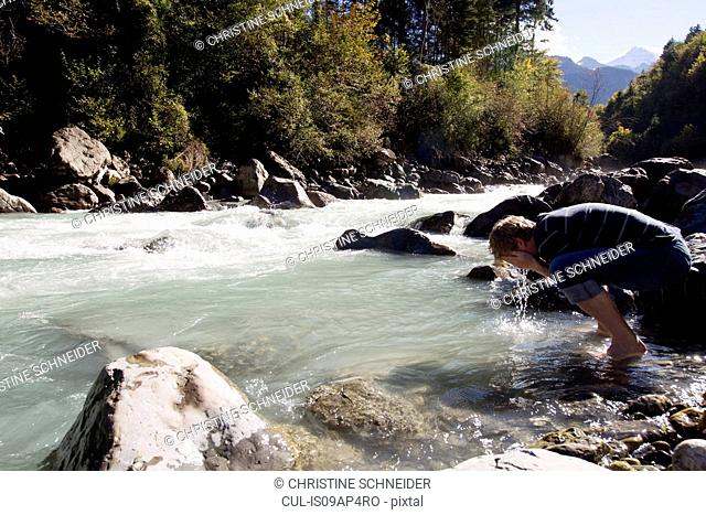 Male hiker washing his face in river, Lauterbrunnen, Grindelwald, Switzerland