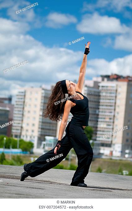 Beautiful teenage girl dancing hip-hop over urban city landscape